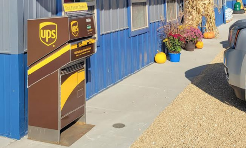 Our brown & yellow UPS drop off box located outside our blue & grey walled store. 